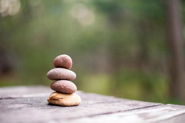 Pebbles stacked up on top of one another with green forest in the background