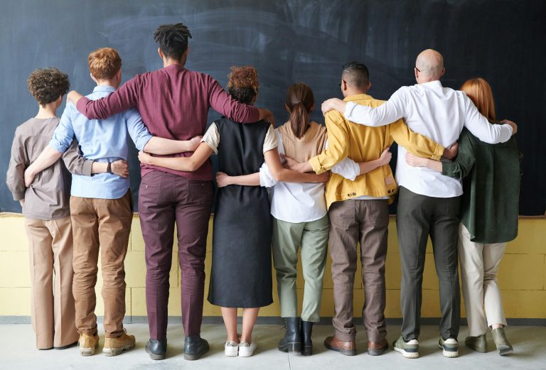 A group of people hugging in front of a blackboard